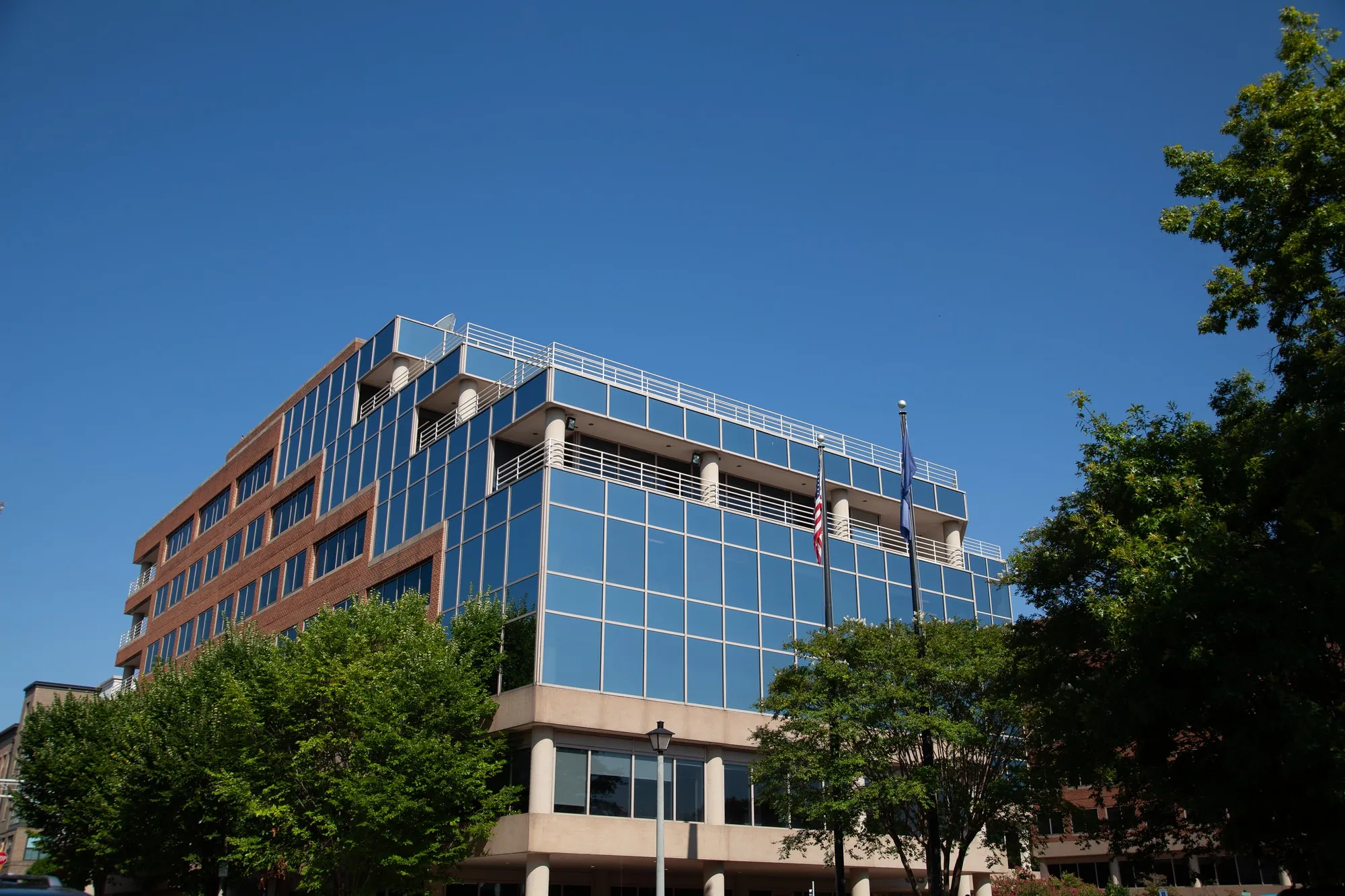 The glass front of 66 Canal Center Plaza in Alexandria, home of the Cypress International office, with flags flying at the entrance